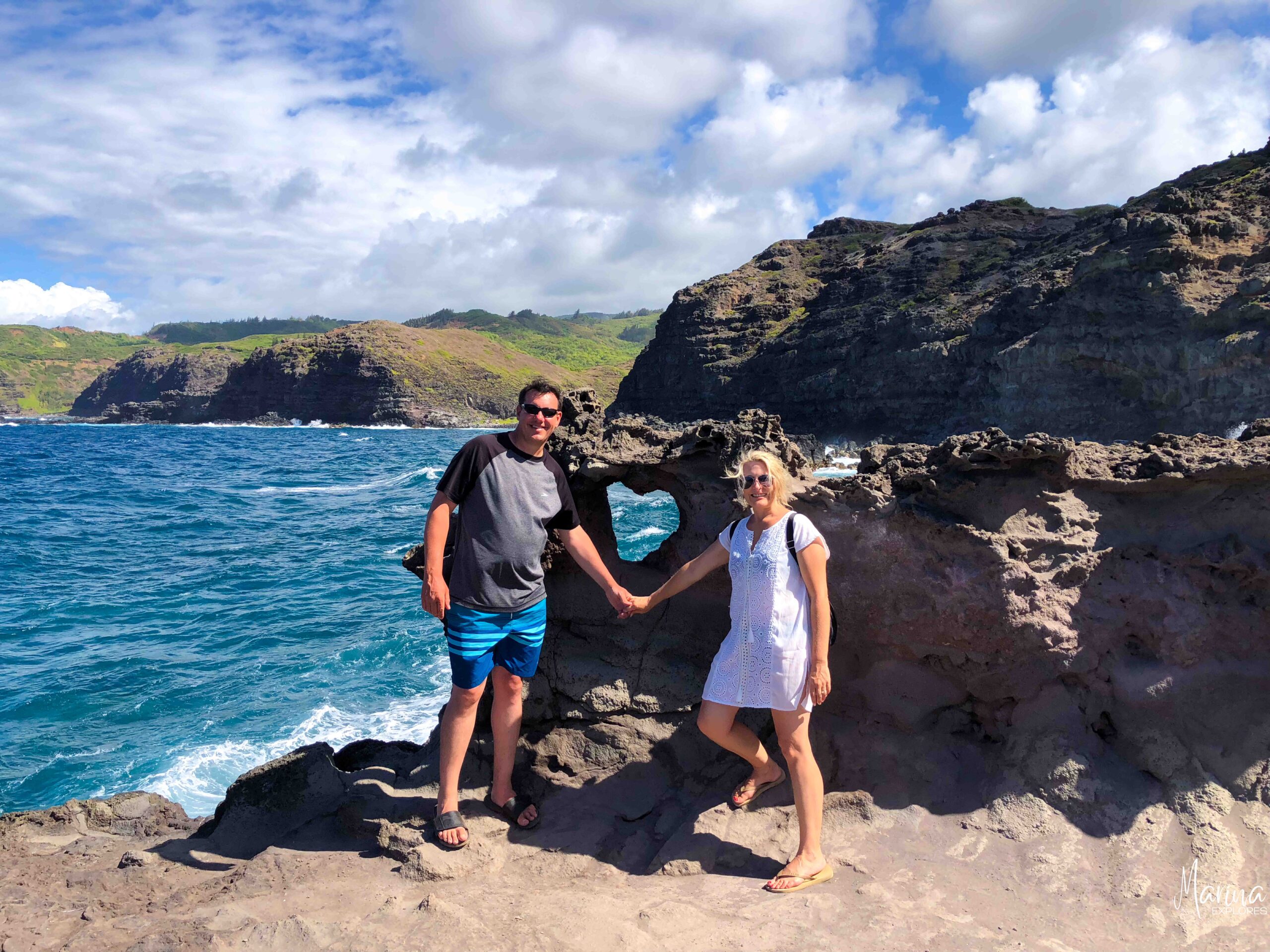 Marina and husband holding hands in front of heart rock in Maui