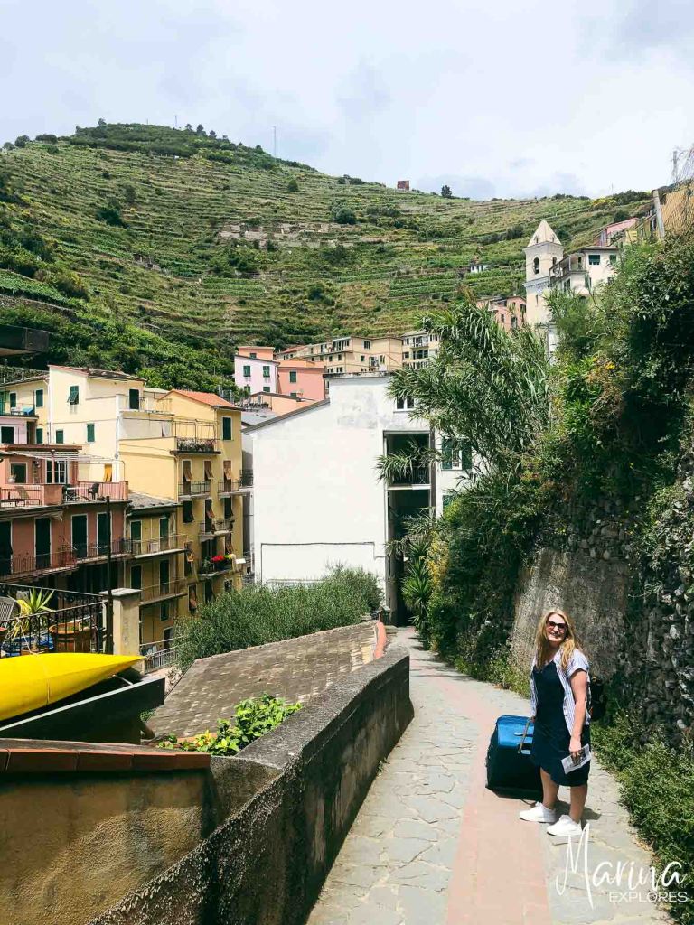 Marina rolling suitcase up steep street in Manarola, Cinque Terre, Italy