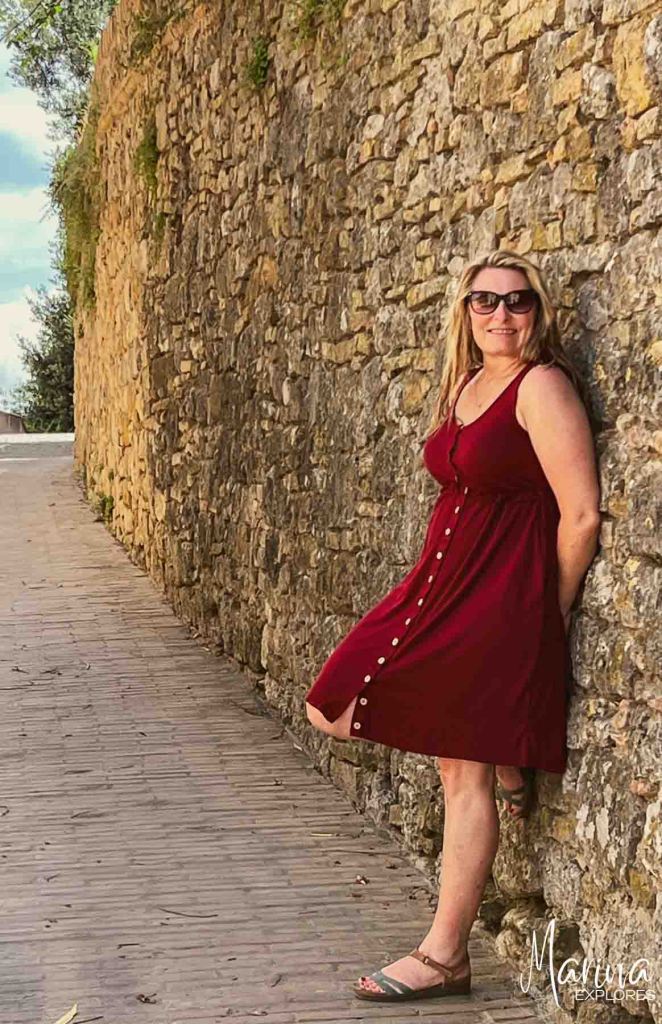 Marina wearing red dress leaning against wall in San Gimignano near Florence, Italy